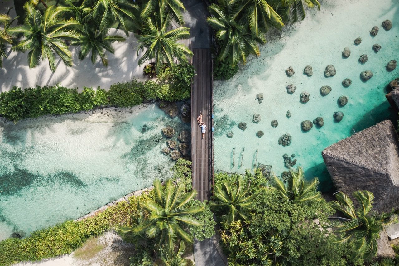 Aerial view of a couple on a walkway above the lagoon at InterContinental Bora Bora Resort & Thalasso Spa